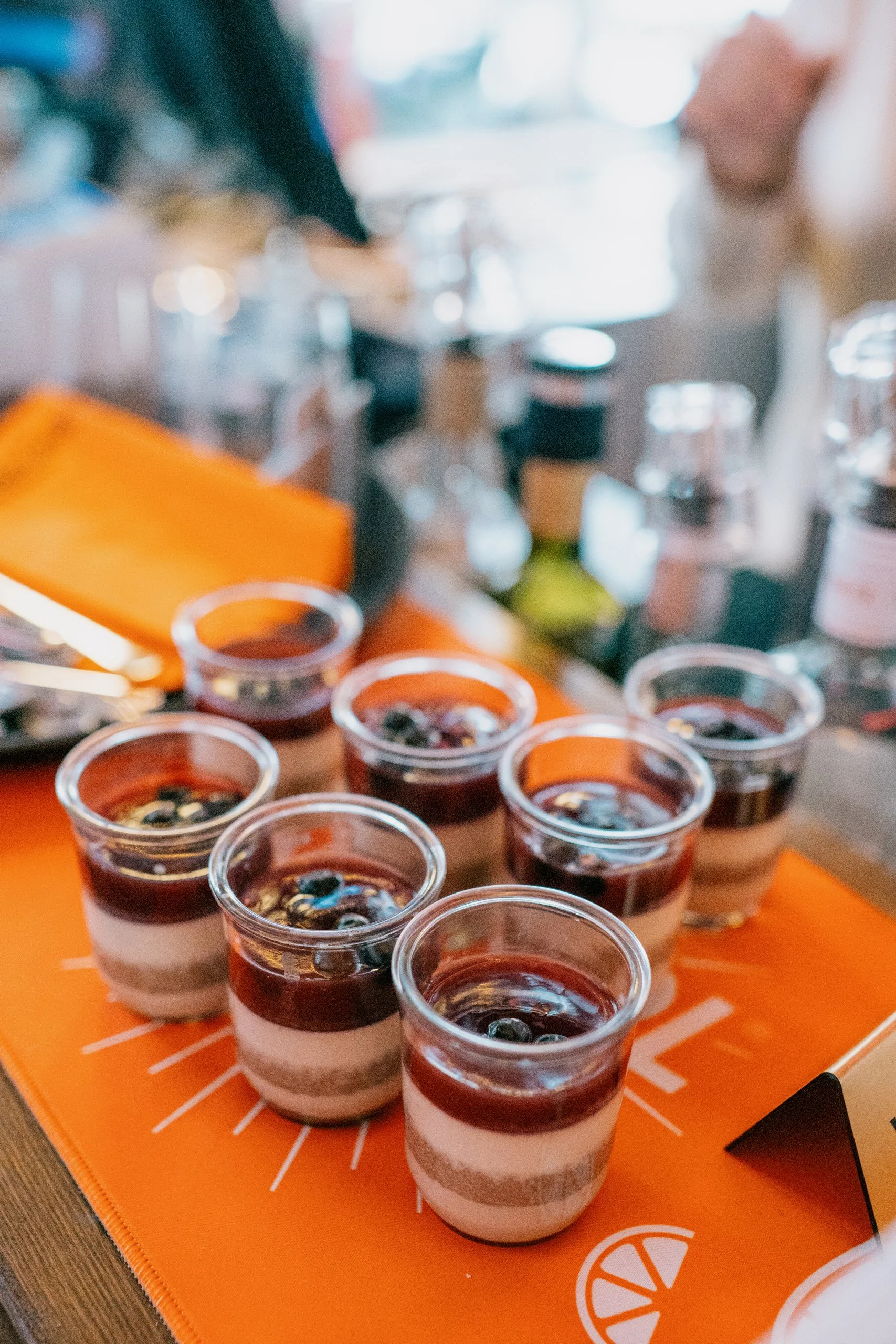 Small layered desserts topped with blueberries on an orange table mat.